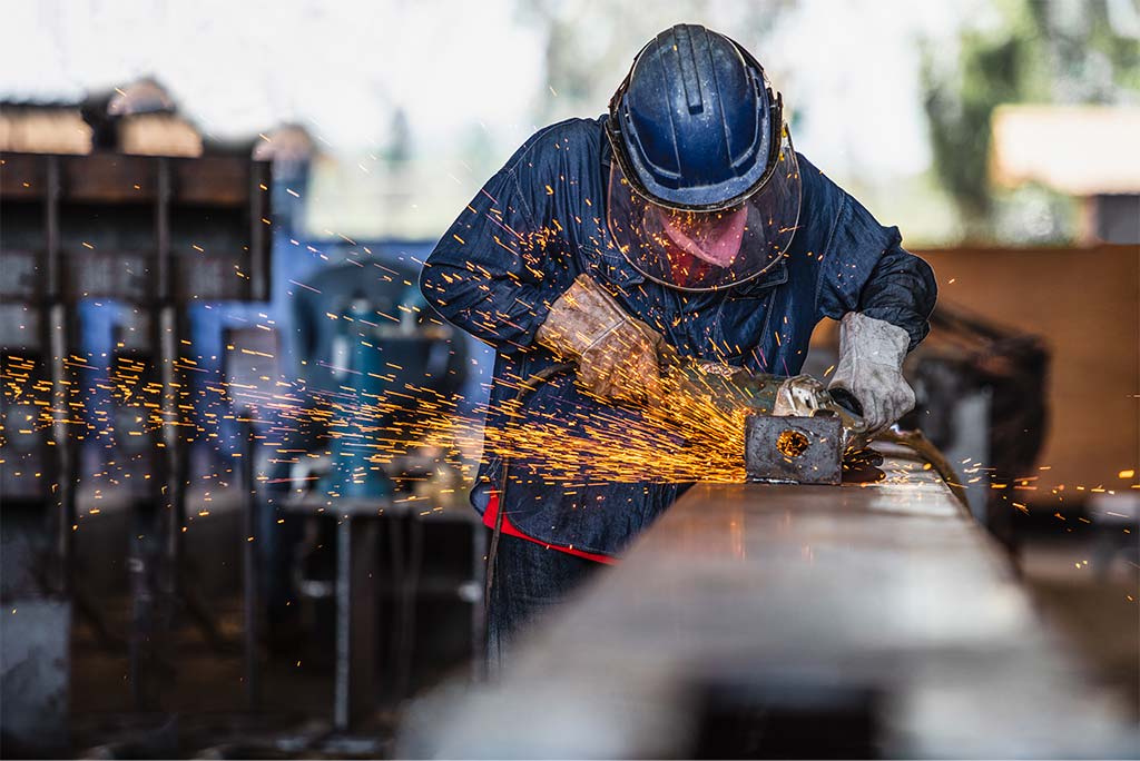 Arbeiter schleift Metall mit Funkenflug in Werkstatt.